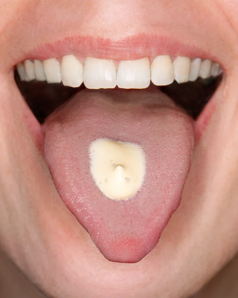 Närbild på en mun med en klick sås på tungan.